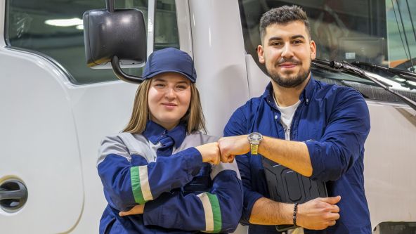 Zwei Azubis stehen vor einem LKW.